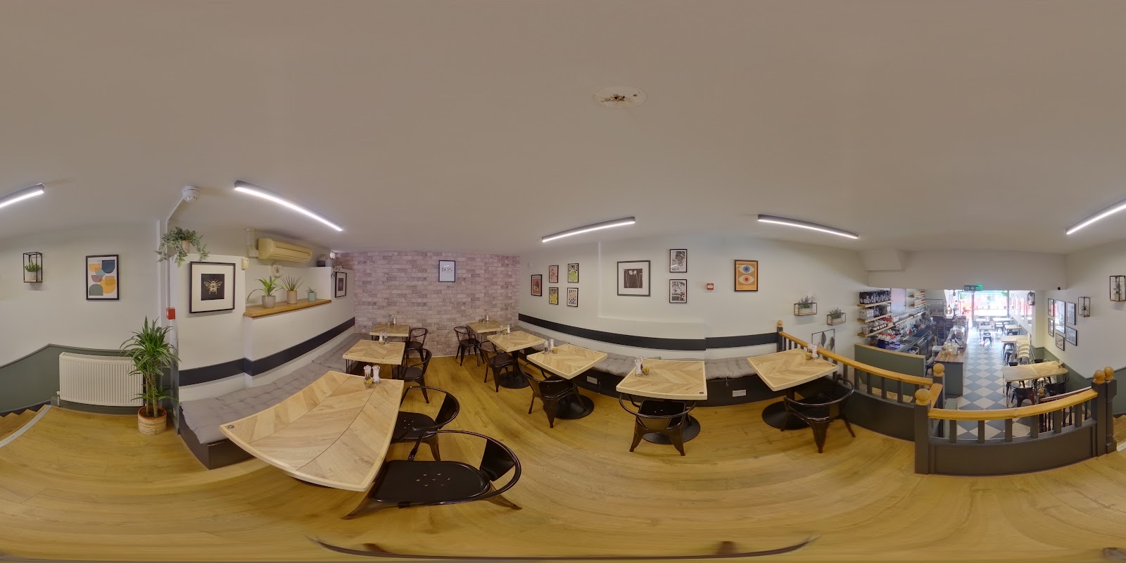 The cafe's dining room with pale walls, framed pictures, wooden tables and dark chairs